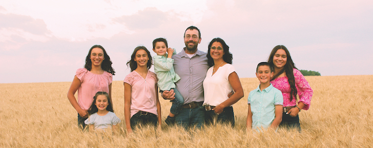 Greg and Sarah Stamp, contributors to Canada’s pedigreed seed industry, stand in a field with their six children of various ages.