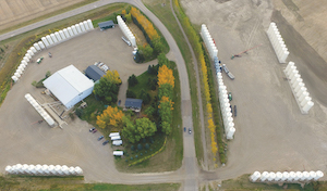 An aerial view of Stamp’s Seed operation, with many white silos, trucks and trailers, and farm buildings in a rural area.